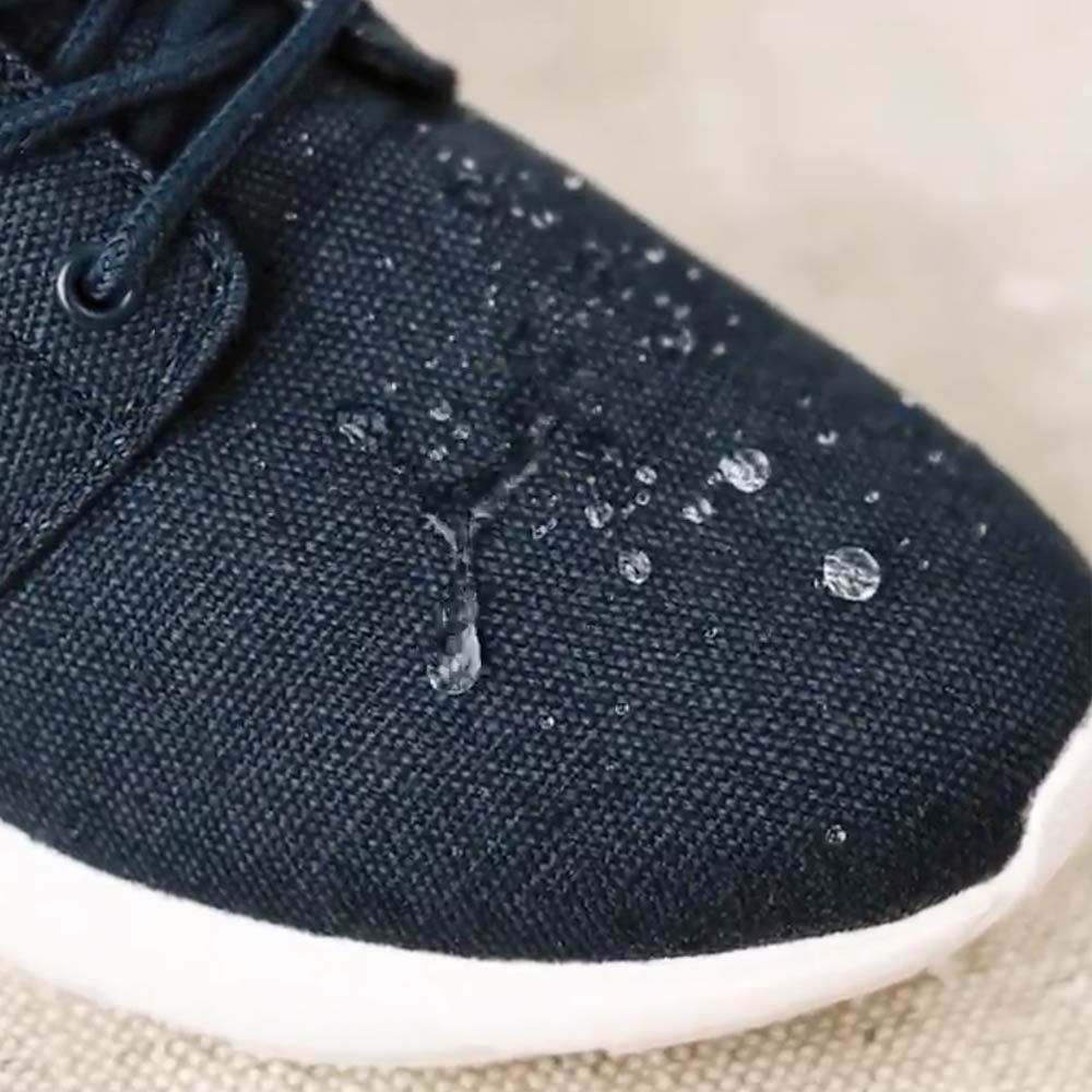 Close-up of the water-resistant feature of the 8000 Kicks Low Top Explorer V2 Black and White sneaker, with water droplets on the black hemp fabric.