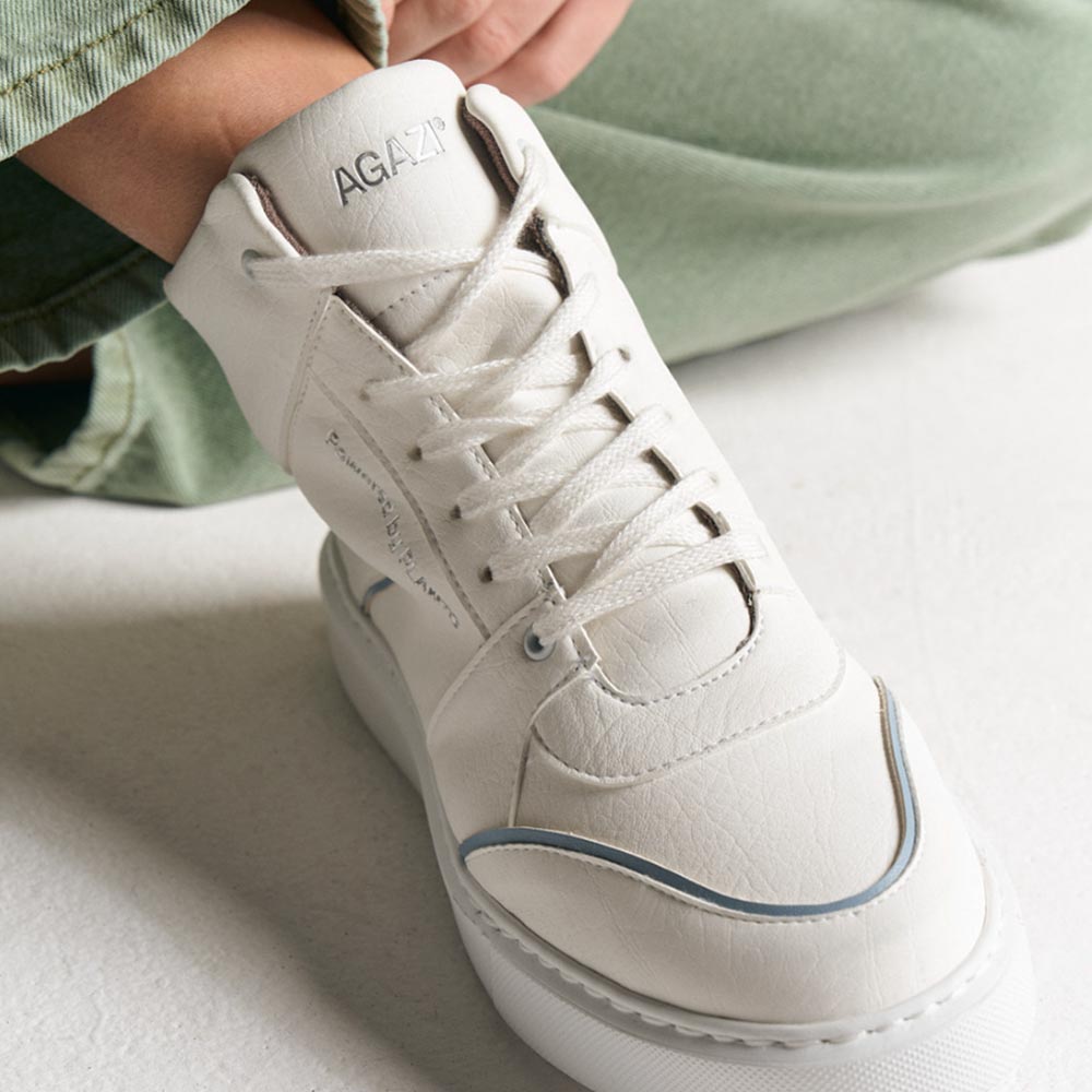 Close-up of model wearing AGAZI EMI High Top sneakers in white and blue. Sustainability shoes. Environment friendly shoes.