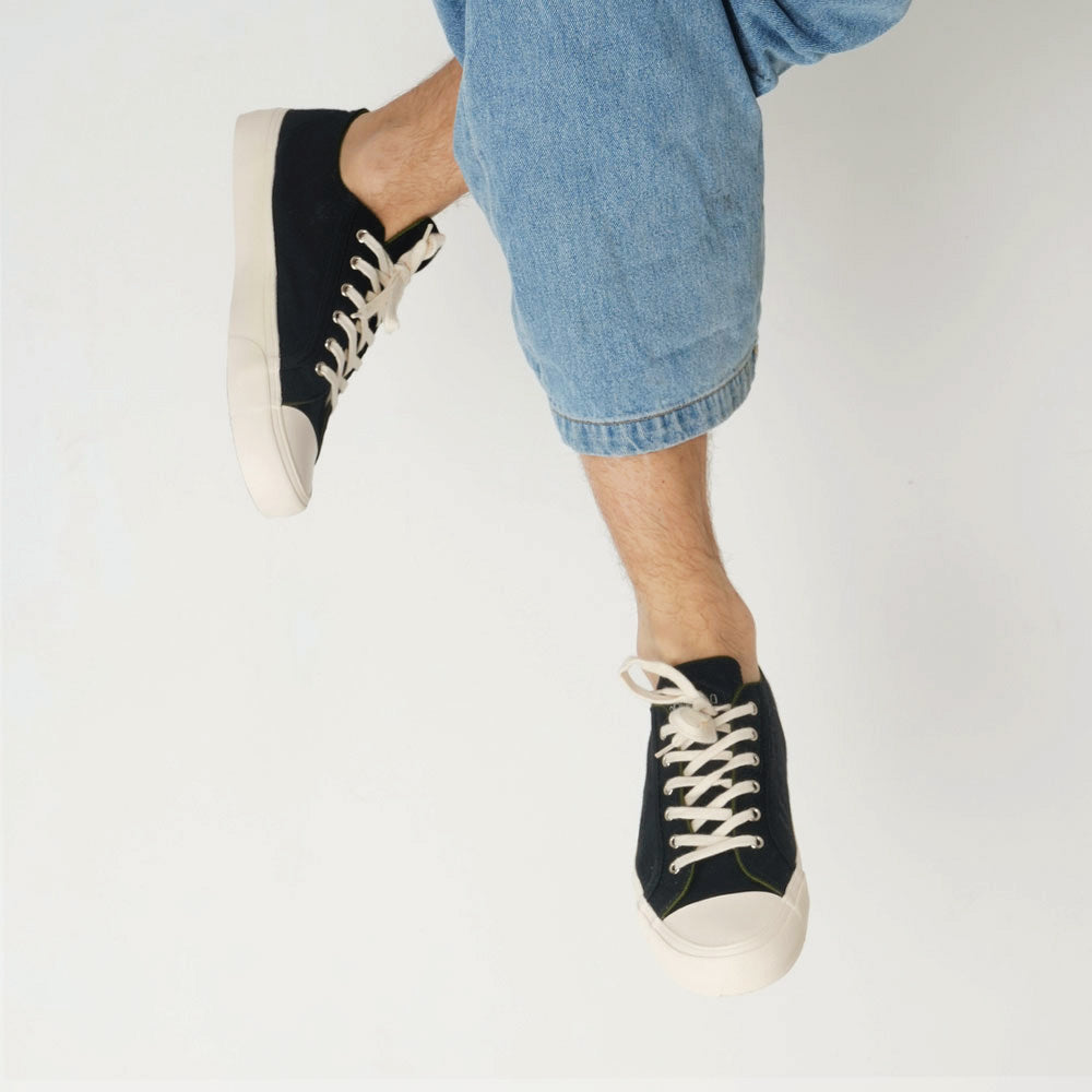 Lifestyle shot of a person wearing Bamburista Low Top GrassHopper Corvino Black sneakers, demonstrating the stylish and sustainable bamboo fiber design.