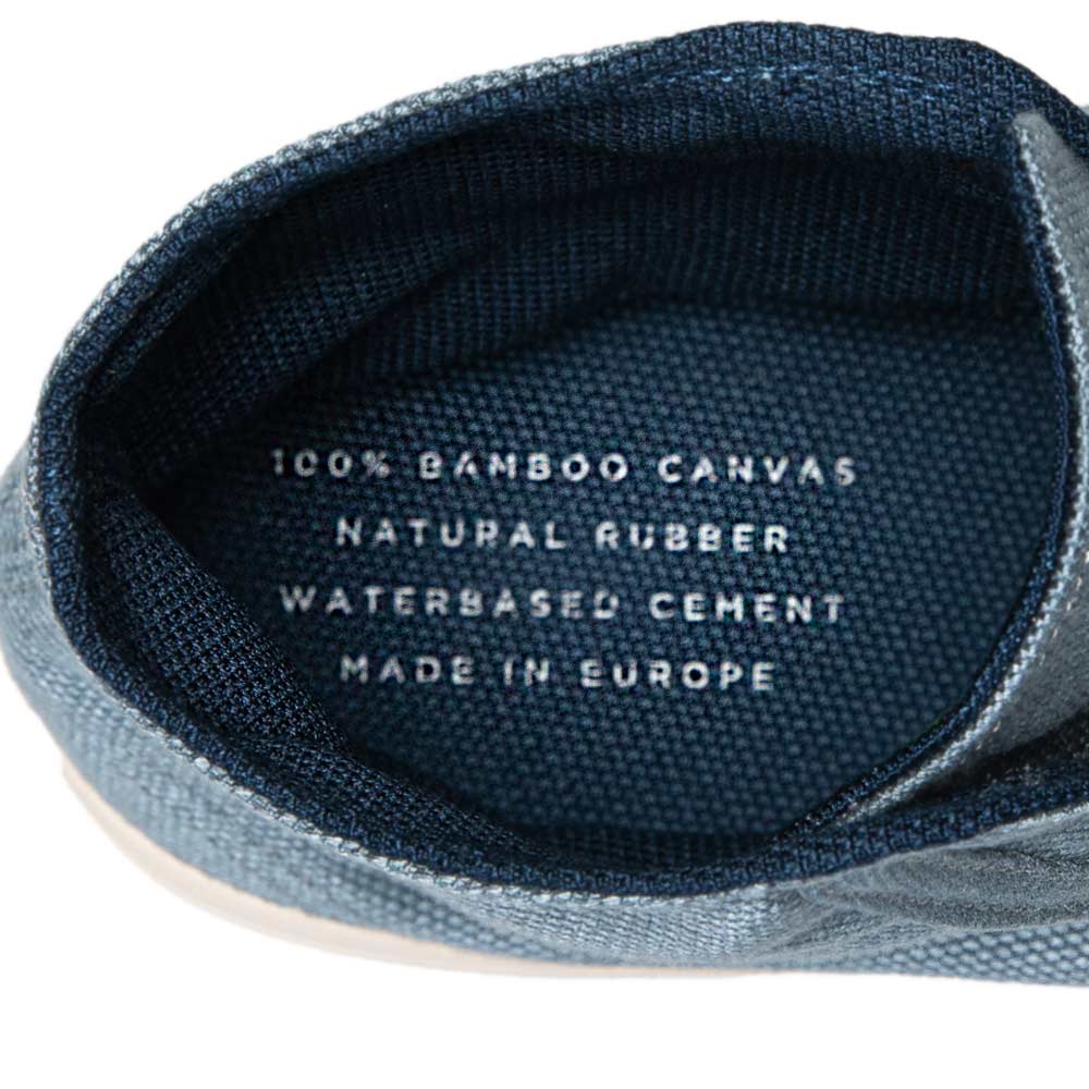 Close-up inside view of Bamburista GrassHopper Kawasemo Denim sneaker, displaying "100% Bamboo Canvas, Natural Rubber, Waterbased Cement, Made in Europe" text.