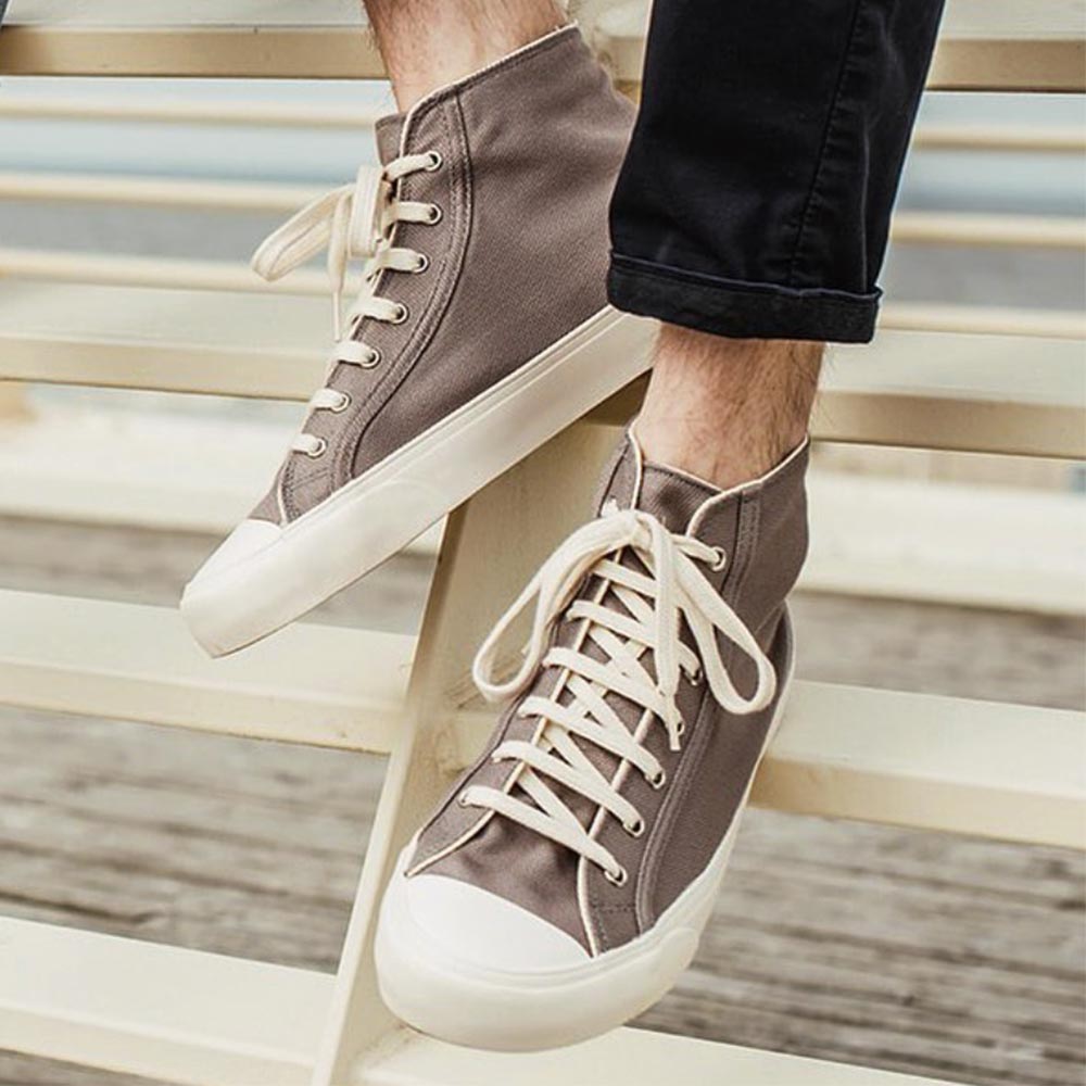 Close-up of person wearing Bamburista GrassHopper Grey high-top sneakers, made from bamboo fiber textile, sitting on a bench.