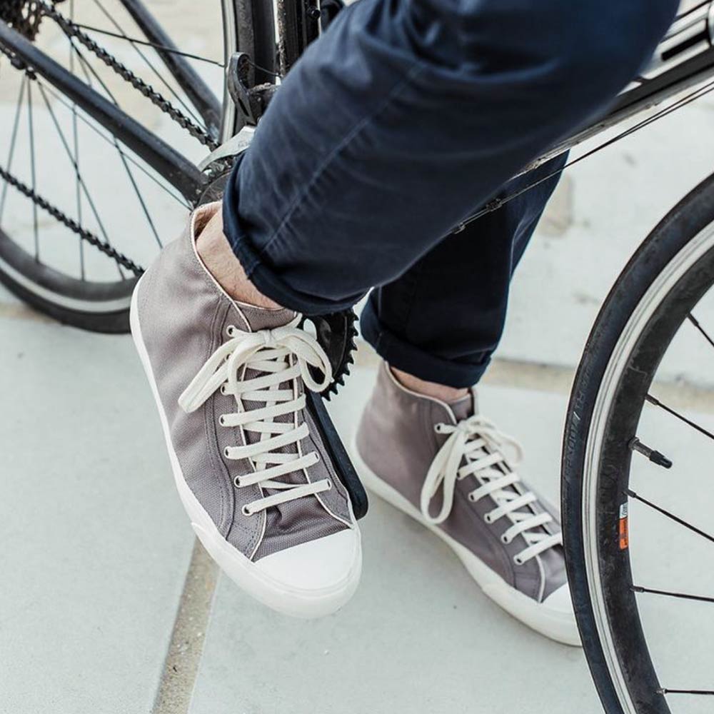 Person wearing Bamburista GrassHopper Grey high-top sneakers while riding a bicycle. The shoes are made from sustainable bamboo textile.