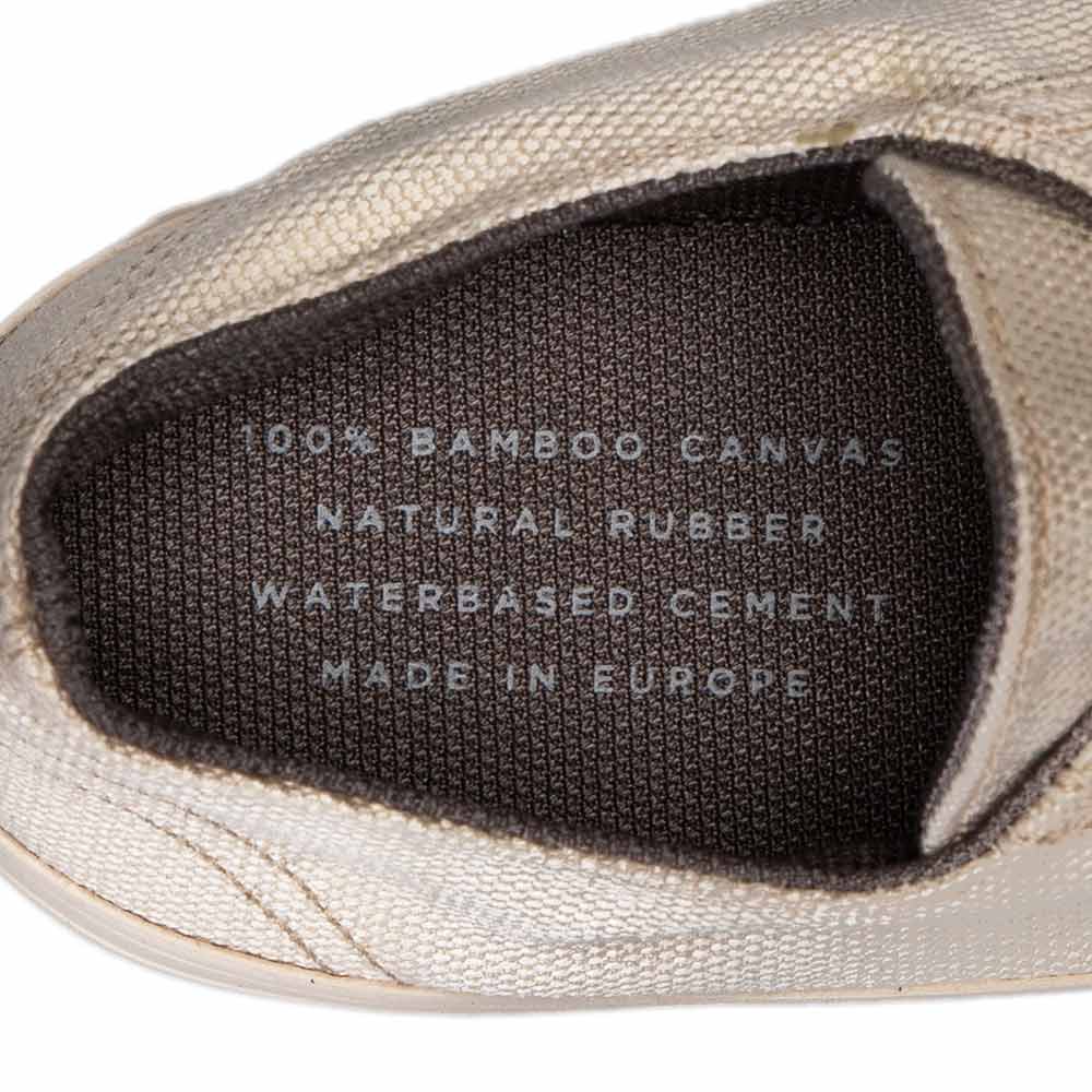 Close-up of the inner label of Bamburista Low Top GrassHopper White Sand sneaker. Label highlights the use of 100% bamboo canvas, natural rubber, and water-based cement, emphasizing sustainability.