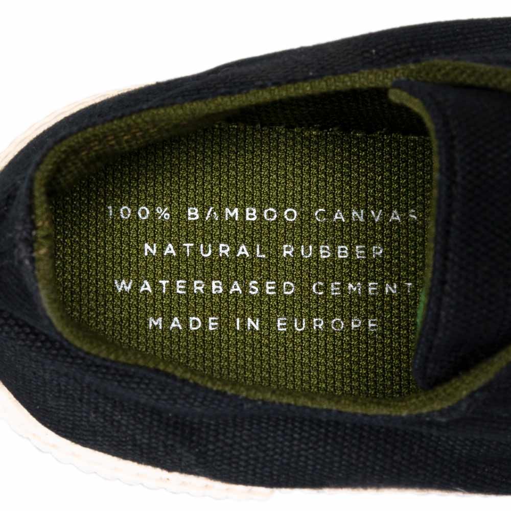 Inner Label of Black Sneaker: Close-up view of the inner label of a Bamburista sneaker, highlighting the use of 100% bamboo canvas, natural rubber, and water-based cement. Made in Europe, emphasizing the sustainable shoe design.