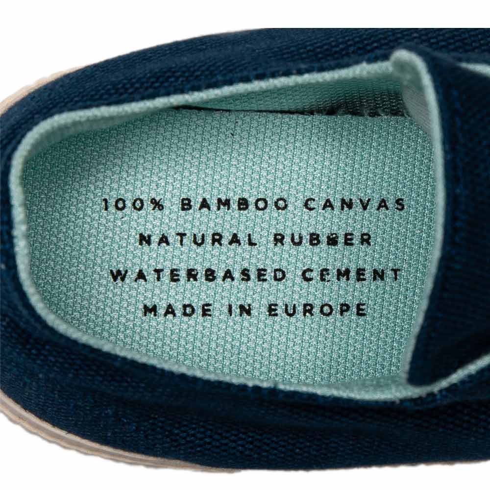 Inside view of Bamburista Blue sneaker: The inner sole of the sneaker with text printed on it, indicating "100% bamboo canvas, natural rubber, water-based cement, made in Europe."