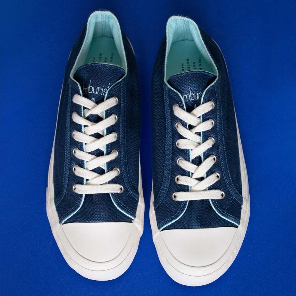 Pair of Bamburista Blue sneakers: A pair of women's sneakers in blue bamboo fiber textile, displayed against a blue background. The shoes feature white laces and sustainable rubber soles.