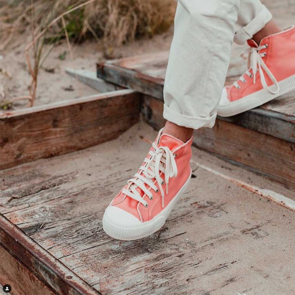 Close-up of a woman walking down wooden steps, wearing Bamburista Flamingo sneakers, showcasing the shoes' eco-friendly bamboo fiber textile and versatile style.