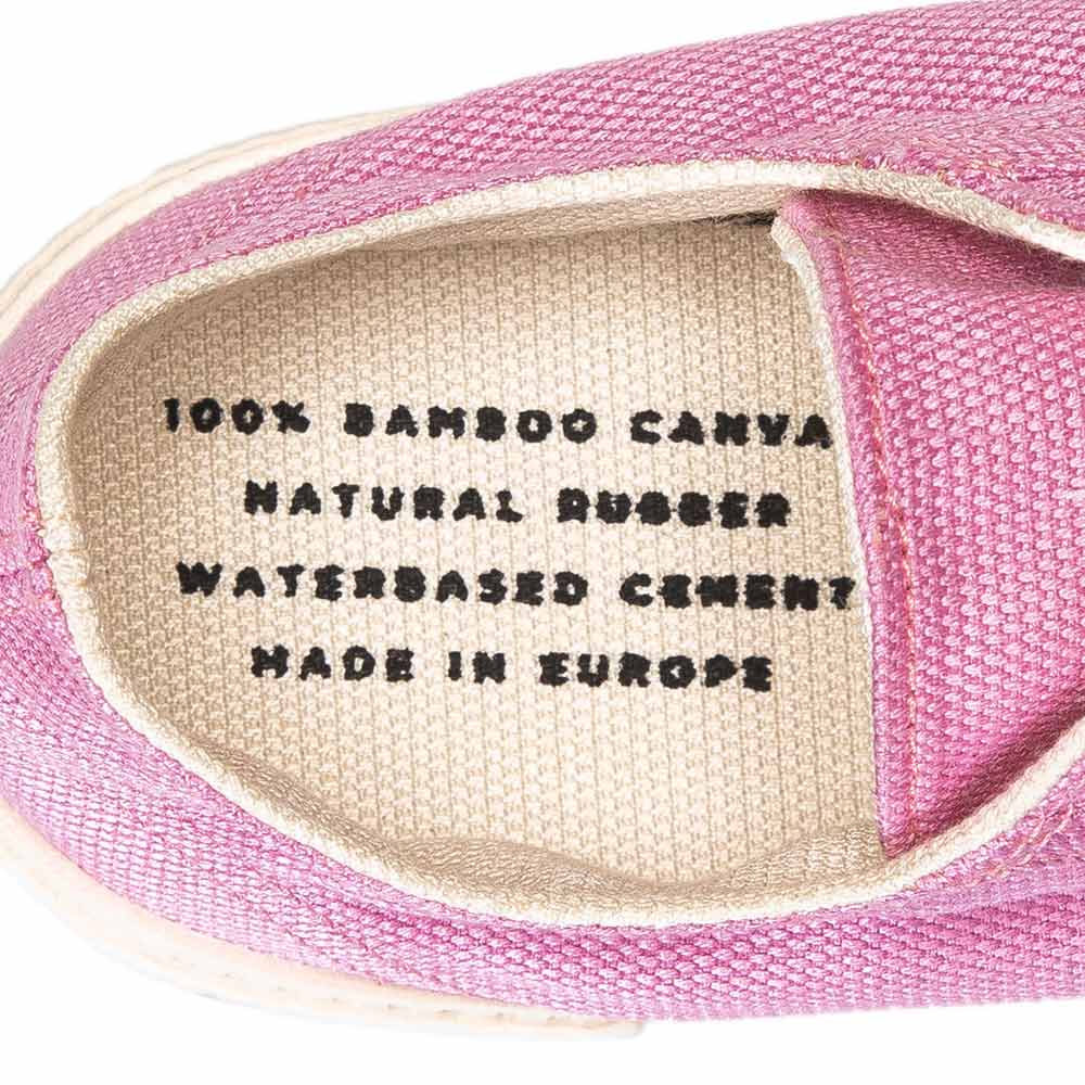 Close-up view inside the pink Bamburista sneaker, showing the text "100% Bamboo Canvas, Natural Rubber, Waterbased Cement, Made in Europe" printed on the insole.