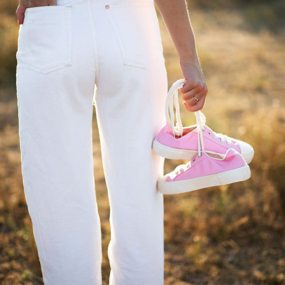 Close-up shot of a person holding pink Bamburista sneakers made of bamboo fiber textile by their laces. The shoes are designed for women and represent a sustainable choice.