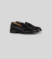 Vegan Loafer - Woman in black leather, versatile for casual and formal outfits, featuring a distinctive U-shaped pattern.