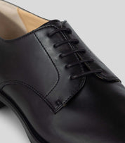 Close-up of a black Vegan Derby - Man shoe featuring an open lacing system and Blake Construction.