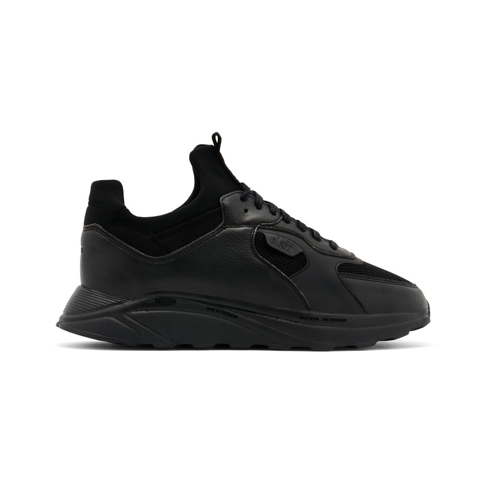 Side view of the ekn Larch Carbon Vegan shoes in all-black with white soles, highlighting sustainable shoe design.