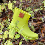 Close-up of Thies Bio Rain Boots in lime green for women, surrounded by foliage, showcasing the vegan boots in a natural setting.