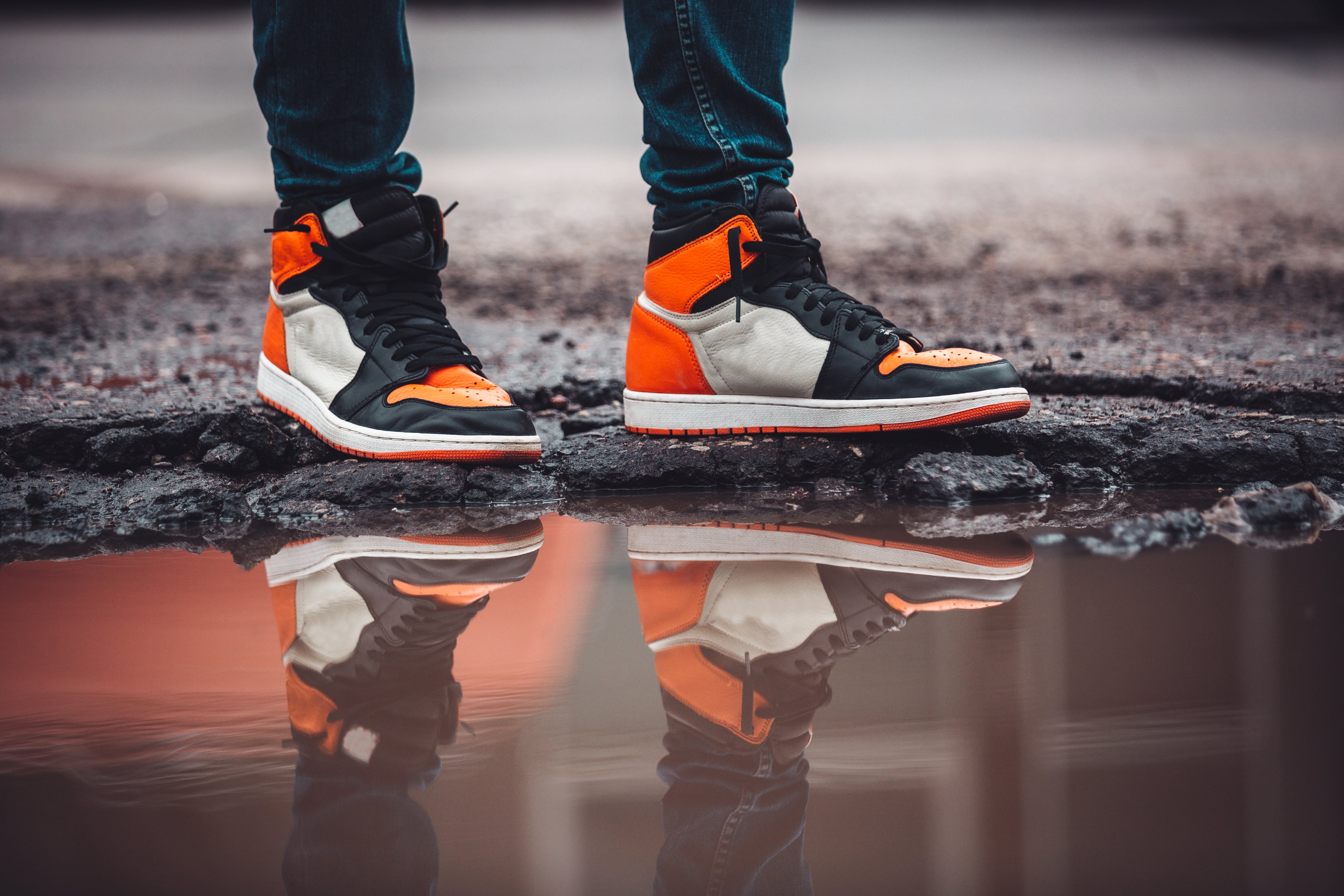 bright-fashion-sneakers-reflect-in-puddle-on-asphalt-street.jpg