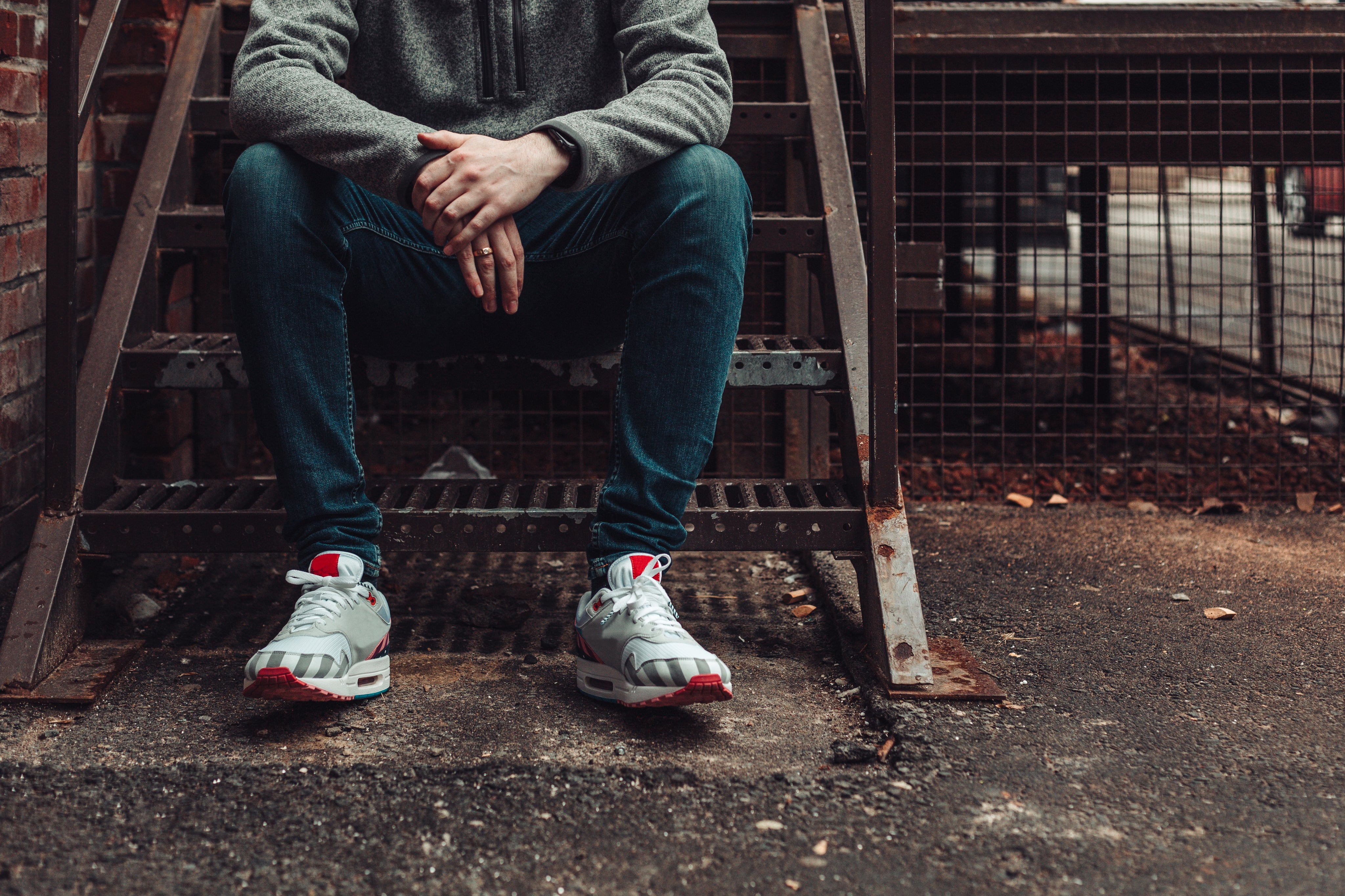 man-in-dark-denim-and-fashion-sneakers-sitting-on-stairwell.jpg