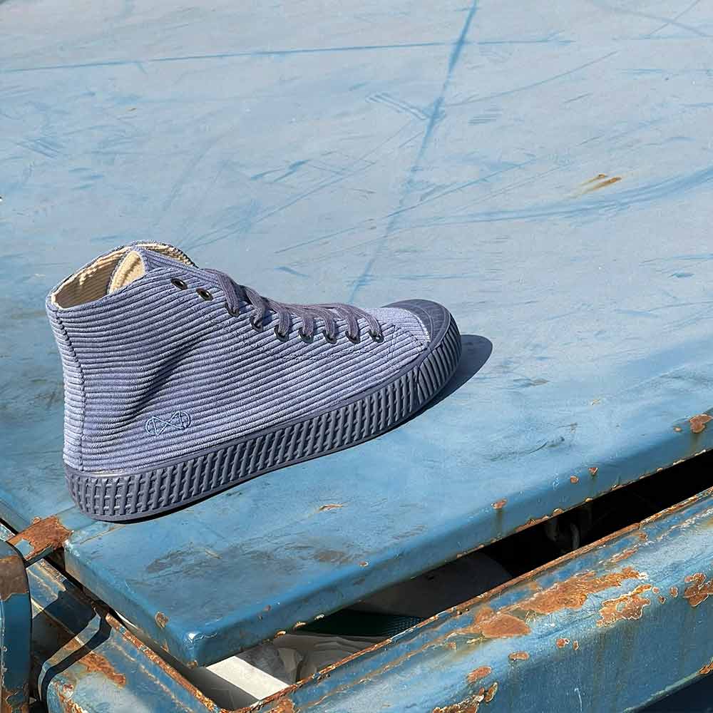 nat-2 Cord Jeans sustainable shoes on a blue surface.